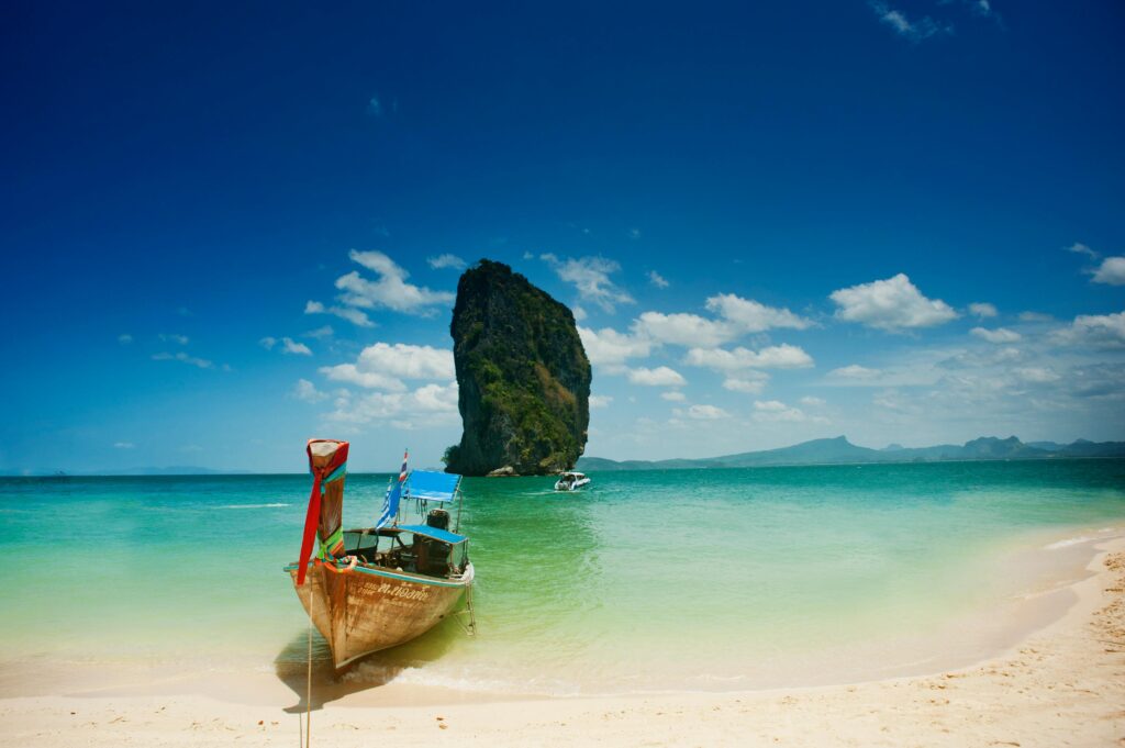 Travel Business Assistance | Thailand | Boat on a beach with rock in background